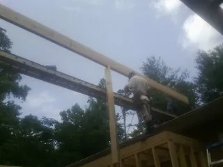 Carpenter setting a ridge beam over a new addition frame — Ice Dam Removal by Roofing Brothers in Lind