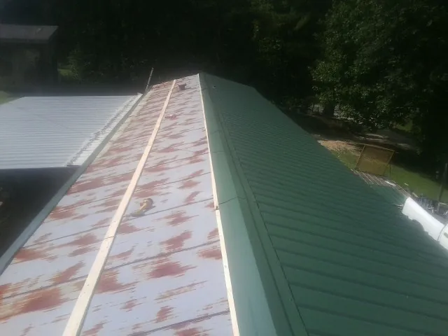 Old rusted panels beside newly installed green metal roofing — Wind Damage Roof Repair by Roofing Brothers in Lind
