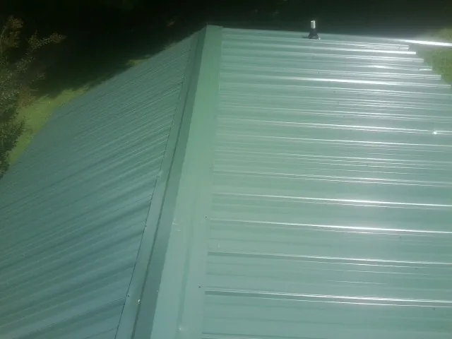 New green metal panels meeting at the ridge of a roof — Flat Roof Repair work by our crew in Lind
