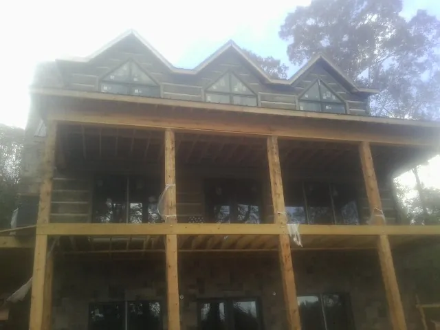 Dormers and porch framing on a large log home under construction — Roof Coating work by our crew in Lind